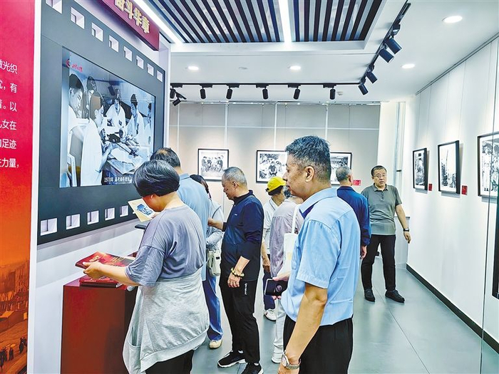 观众津津有味地欣赏图片展画册。夏红 摄