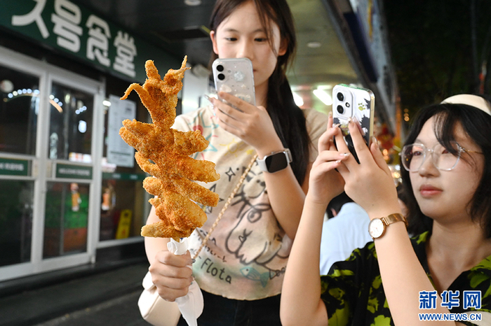 7月13日，顾客在拍摄刚购买的“轰炸”大鱿鱼美食。新华社记者 林善传 摄