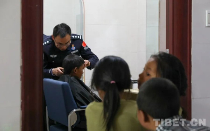 图为民警在便民理发室为当地孩子理发