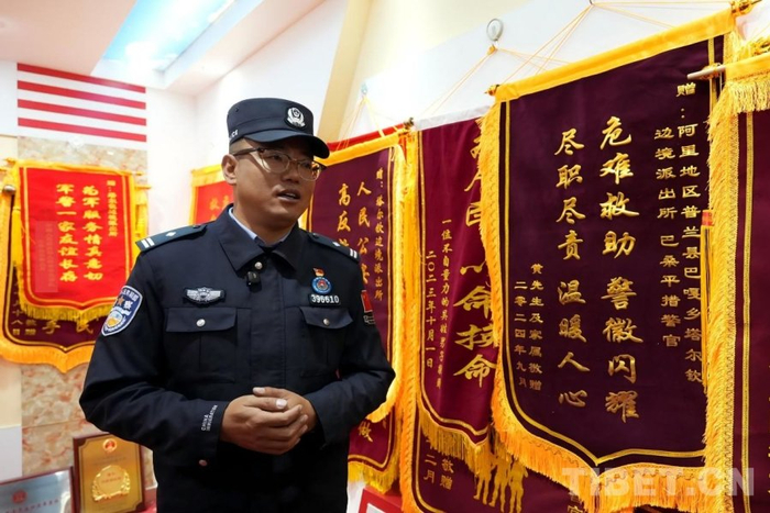 图为塔尔钦边境派出所所长巴桑平措，身旁是黄先生及家属敬赠的锦旗 摄影：边子捷
