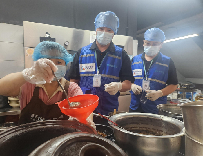 抽检人员对米粉店的卤汁进行采样。顾艳伟/摄