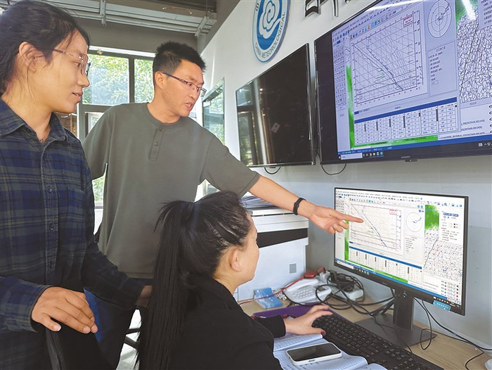 潘贵元（中）和同事讨论气象业务工作。　记者　周婷婷　平措郎加　摄