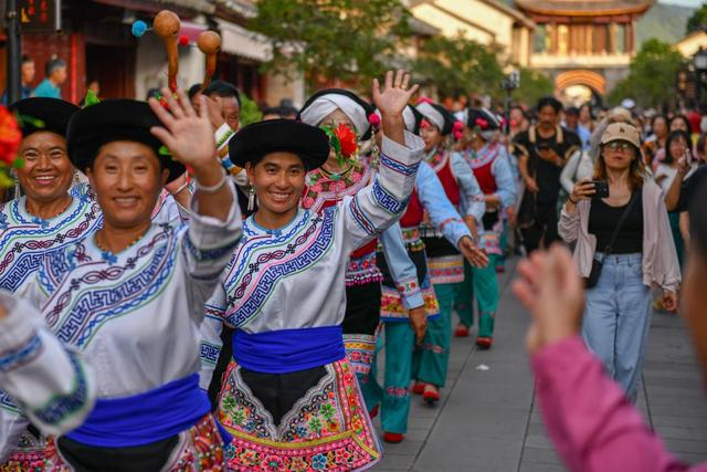 7月18日，彝族打歌队队员在巍山县南诏古街进行巡演时向游客挥手致意。新华社记者 彭奕凯 摄