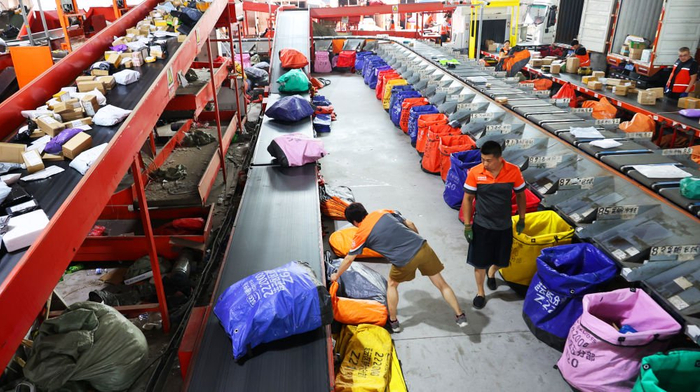 　　江苏省连云港市公共配送中心工作人员分拣、发送快递包裹（2025年6月18日摄）。新华社发（耿玉和摄）