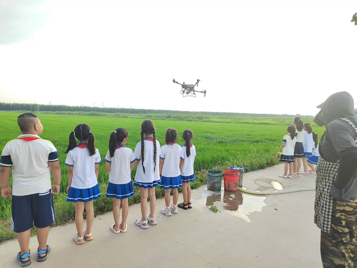 黄庄小学和朝霞路小学学生观察植保无人机喷洒农药（央广网发 天津农学院供图）