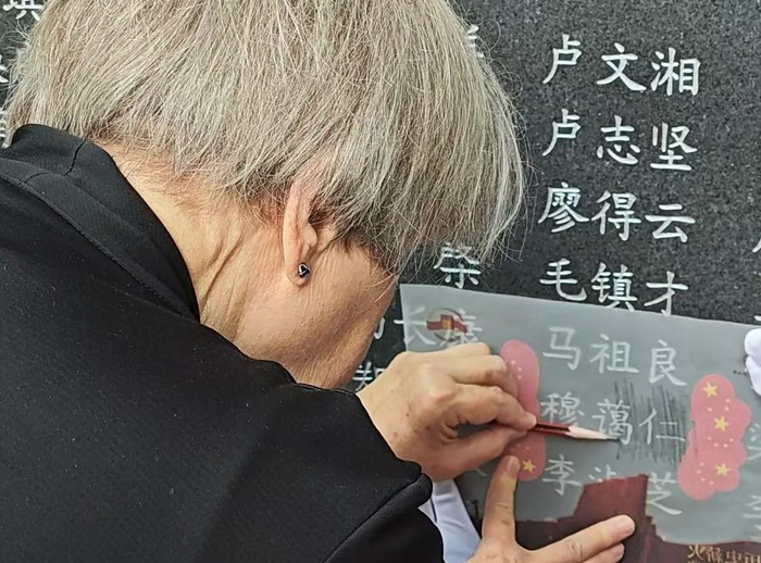 穆言灵在福州抗日志士纪念墙上用铅笔翻拓穆蔼仁的名字。
