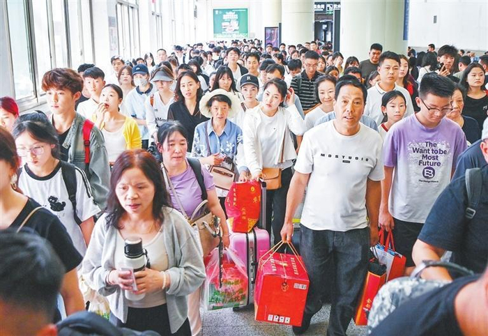     兰州站等候上车的乘客通过检票闸机。