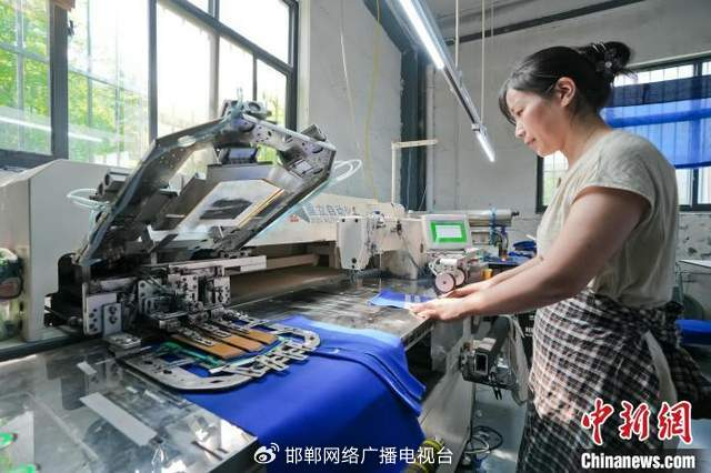 图为7月15日，河北弘润服饰有限公司的工人正在使用全自动贴袋机赶制来自海外的订单。 杜昕雨 摄