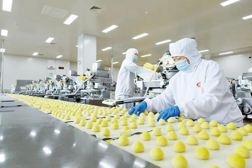     7月21日，在青龙满族自治县双合盛生态农产品有限公司的生产车间，一个个金黄色的黏豆包排队走下生产线。 本报记者 李 巍摄