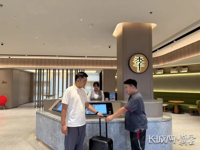 河北顺丰速运工作人员（右）到酒店收取外地游客要寄送的行李。