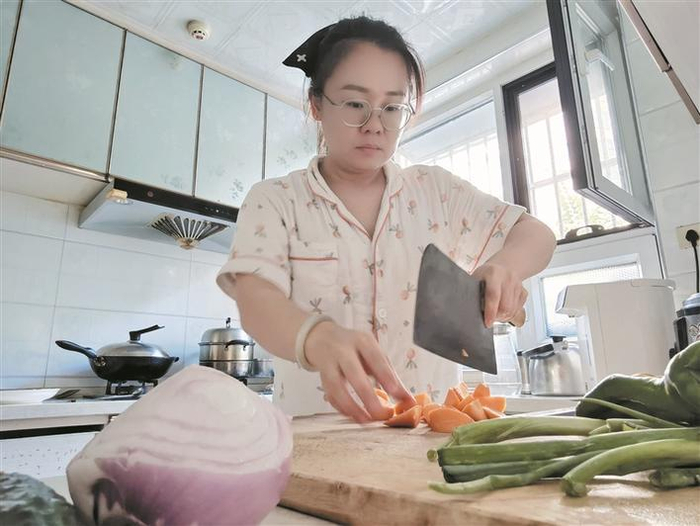     7月24日，周婷婷在厨房准备做大盘鸡的食材。    蒲子璇  摄