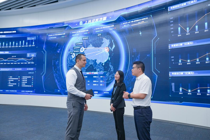 在上合经贸综服平台工作的乌兹别克斯坦小伙赛义德（左一），在与客商交流。（□记者 白晓 报道）