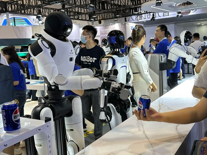 （观众现场体验智元机器人递可乐 财联社记者摄）
