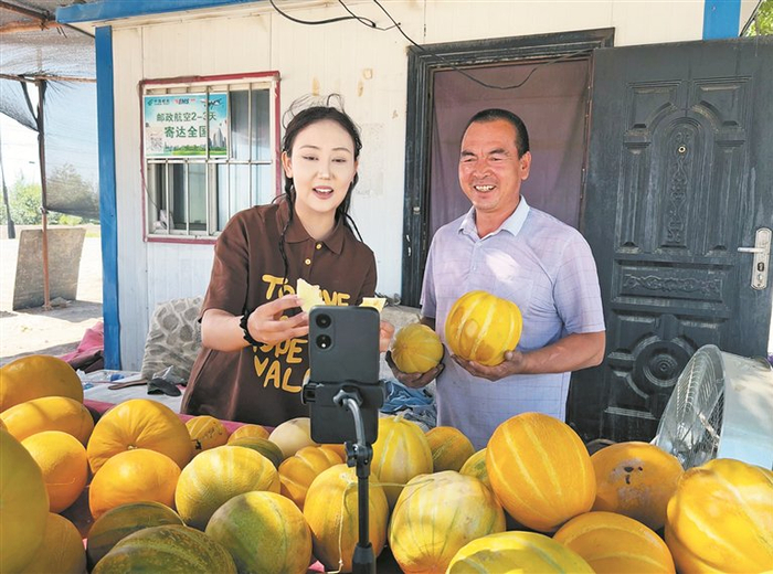     7月23日，六师芳草湖农场三十三连职工毛青林（右），同当地网红一起直播销售自己种植的老汉瓜。    胡阿尼西·巴合提  摄