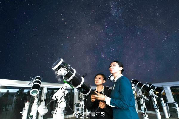 6月12日，宁夏中卫沙坡头景区的阵列式天文观测站，沙漠观星师曹颖（右）协助游客使用反射式望远镜观星。受访者供图