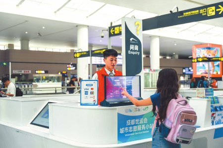 设在成都地铁站内的世运会城市志愿服务小站前，外籍游客正通过翻译机咨询出行信息。成都轨道集团供图