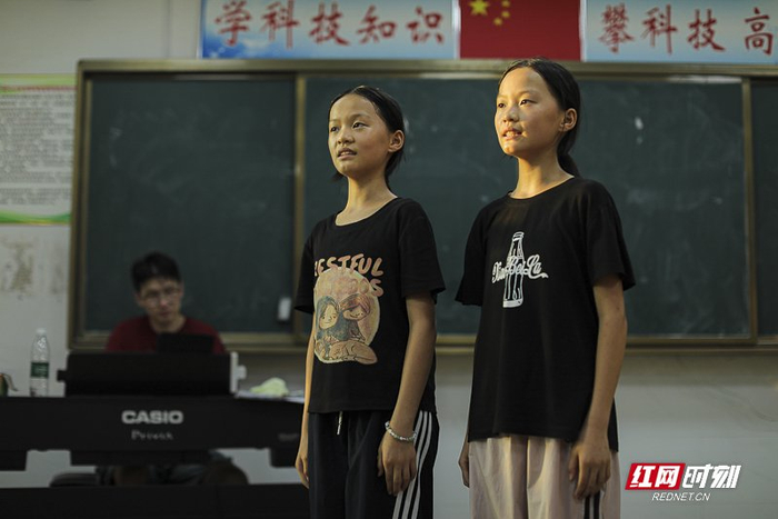 龙市中小合唱班里的双胞胎姐妹龙可涵和龙可滢在接受老师们的指导。