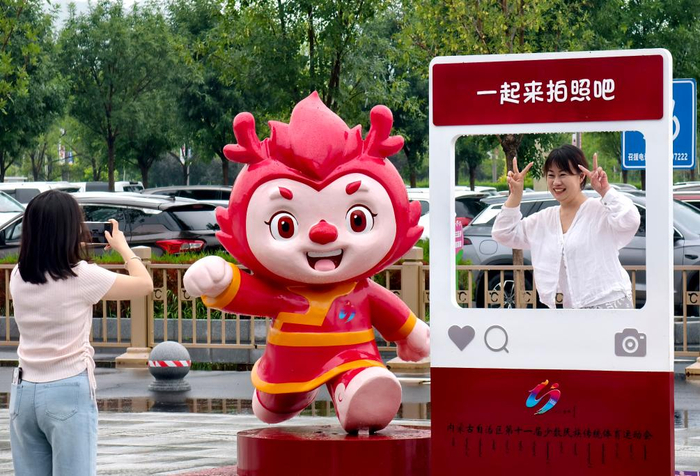7月25日，两名游客在赤峰机场前的赛会吉祥物雕塑处留影。新华社发（曹政 摄）
