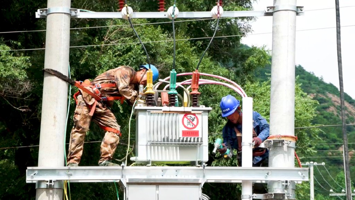 ▲7月27日，国网冀北承德围场县供电公司员工在蓝旗卡伦乡望道石村对变压器进行维护消缺。刘春学 摄
