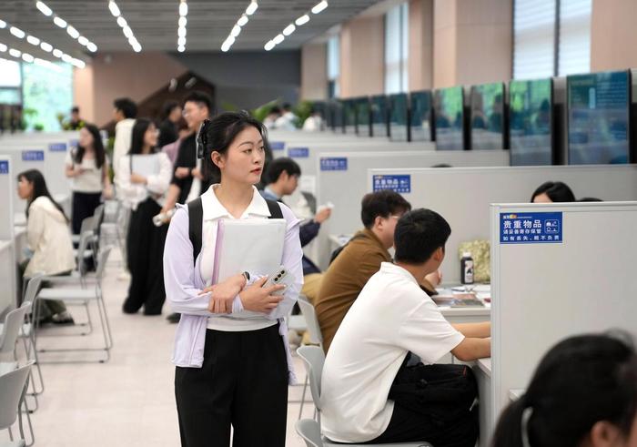 一名求职者(前左)在浙江省杭州市招聘会现场寻找心仪的工作岗位。新华社记者 韩传号 摄