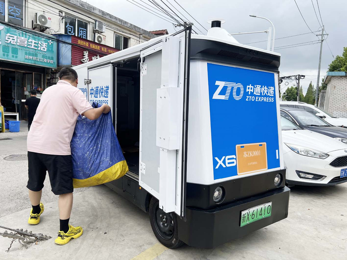 无人驾驶物流车准时到达高校附近快递点，工作人员验证接驳信息后开始搬运快件。荣斌 摄