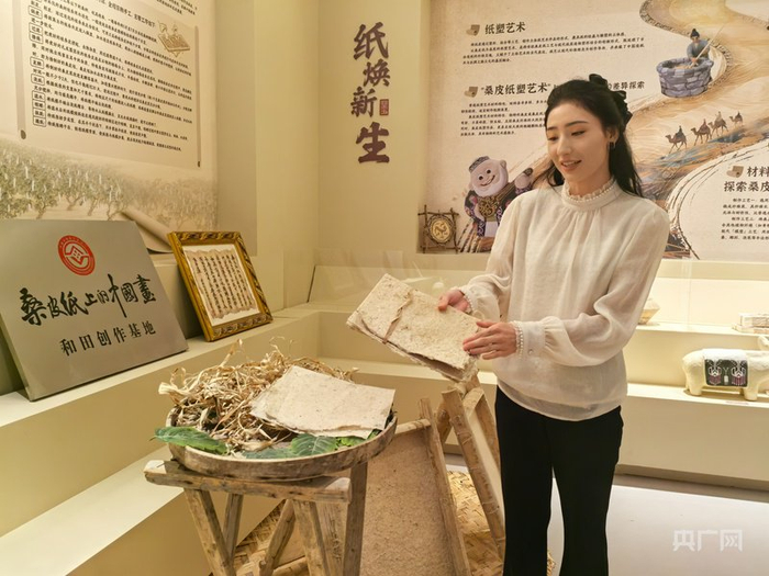 祖力胡玛·如则正在向游客介绍桑皮纸  （央广网记者丁安  摄）