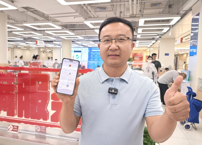 企业负责人展示数字版首张中央厨房食品经营许可证。孔宪良/摄