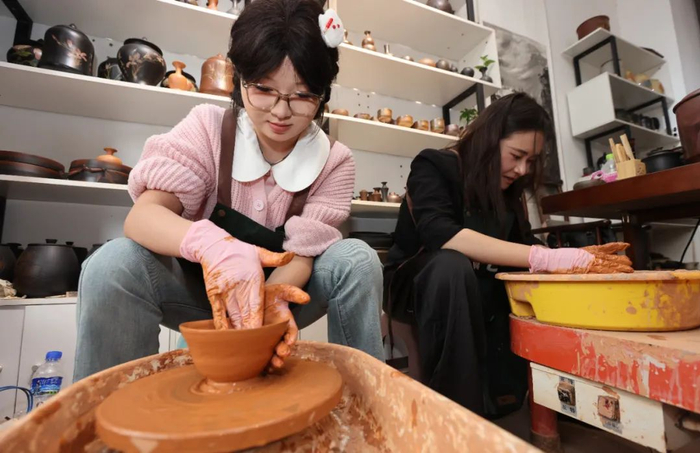 建水古城的紫陶店里，游客正在体验紫陶的拉坯制作过程。黄兴能 摄