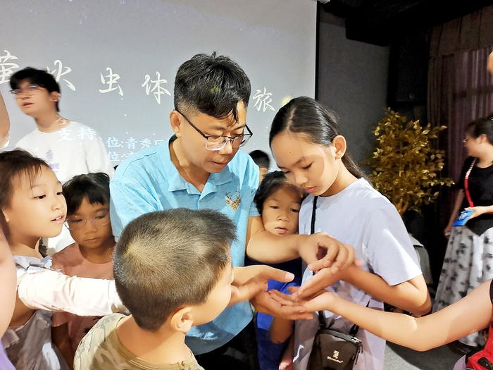     孩子们在工作人员指导下用手指轻触萤火虫幼虫。    本报记者周志英 摄