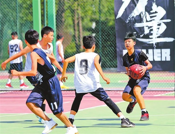 暑假期间，一群学生在郑东新区篮球公园打比赛。