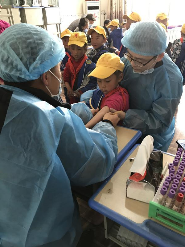 2017年6月，援藏专家赵丹和同事在那曲小学为学生进行包虫病筛查时，一边安慰一边进行抽血化验。图片由赵丹提供