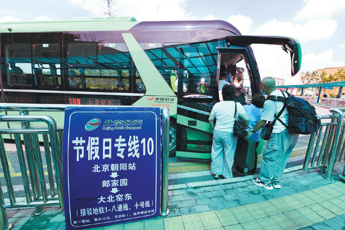 2024年8月18日，北京朝阳站的公交站台，一辆通学公交车承担接驳任务，乘客排队上车。　资料图片/新京报记者　王贵彬　摄