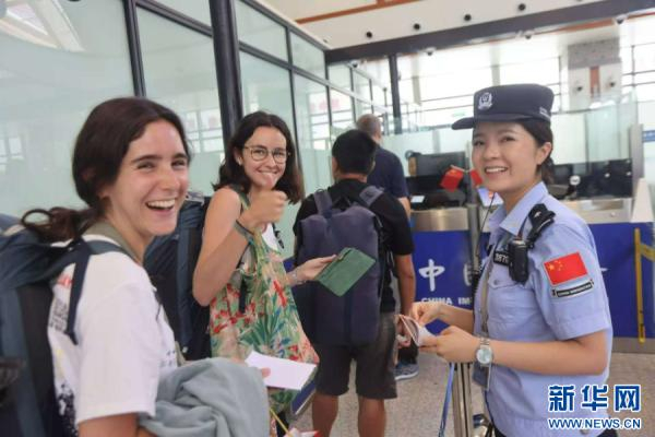 外国留学生在磨憨铁路口岸，为磨憨边检民警优质服务点赞（2024年7月25日摄）。新华网发（黄远飞 摄）