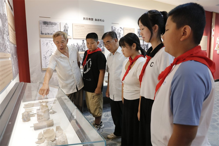 　　8月3日，在遵化鲁家峪村的鲁家峪陈列馆，志愿者刘超（左一）和李自亚（左三）一起为孩子们讲述当年的抗日故事。记者 师源摄