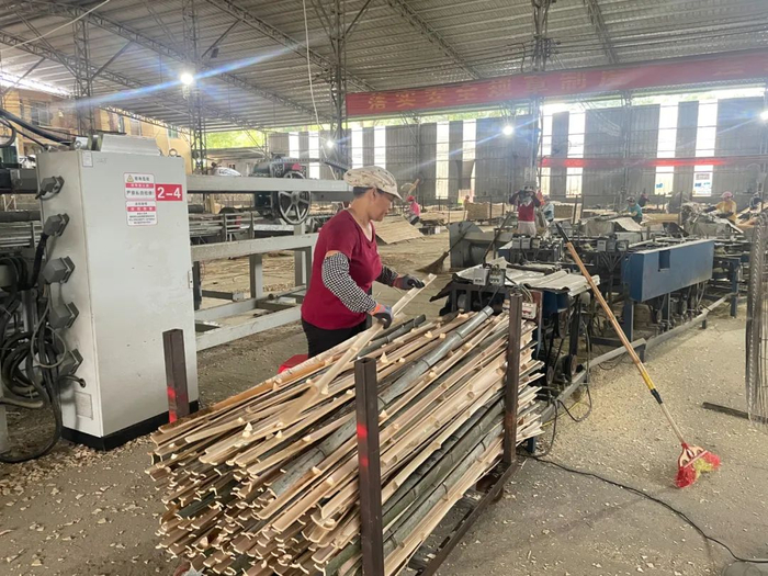 仁化县竹源生态发展有限公司生产车间，工人将毛竹放进破竹机内。