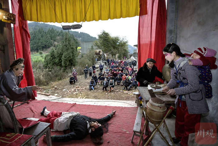 2014年3月，德阳中江县仓山镇宝塔乡，石冬梅背着儿子在乐台打鼓，八个月大的婴儿和着鼓点甜甜睡去。