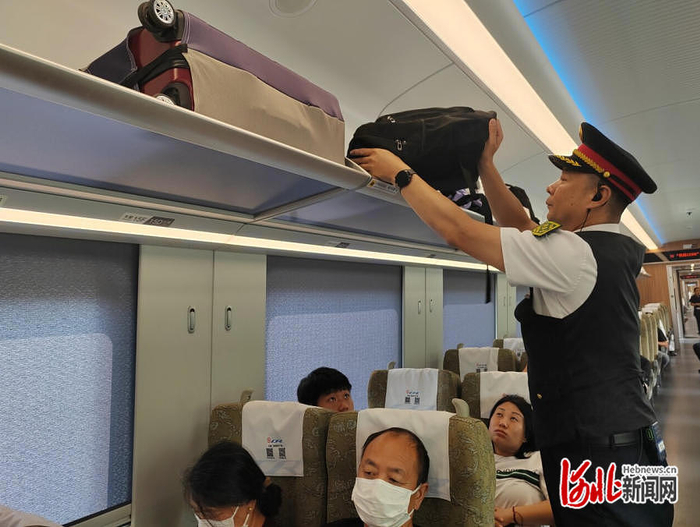 7月27日，从石家庄站开往北京丰台站的C28次列车上，列车工作人员正在整理行李架上的行李。  河北日报记者 方素菊摄