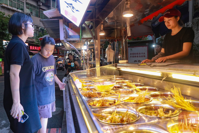 四川农业大学夜市有统一的卫生和食品安全标准等，图为钵钵鸡摊位前的游客。黄刚 摄