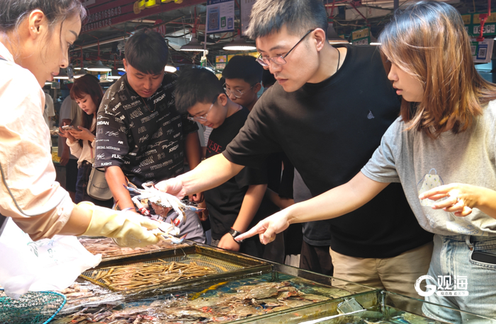 市民在农贸市场挑选梭子蟹。