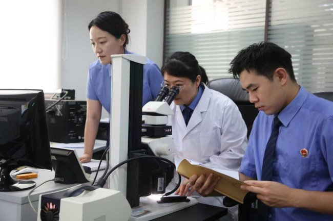 检察技术干警许灵燕（中）向检察官介绍笔迹和印文鉴定等文件检验技术。本报通讯员吕刚摄