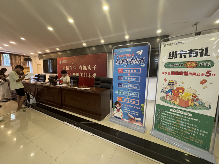 办理现场，立有“绑卡有礼”和档案寄递流程的宣传板