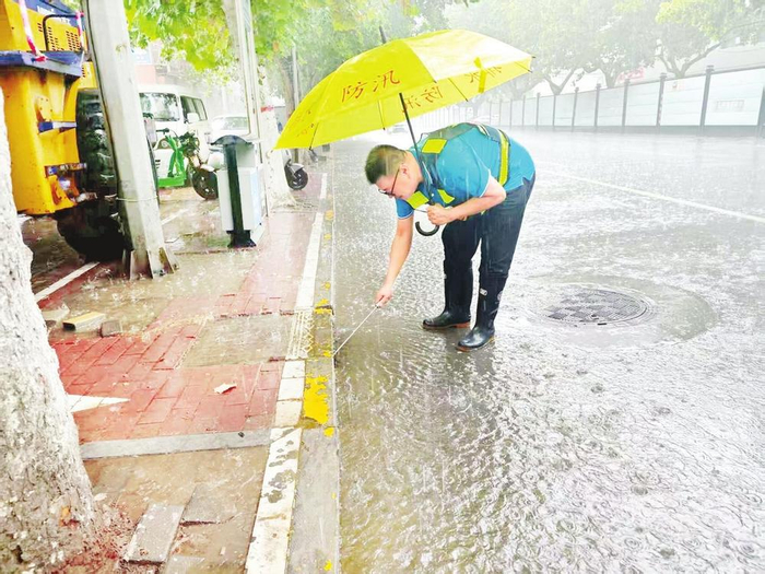         市城市排水管理中心工作人员在大雨中清理收水口。     任宗岩 摄    