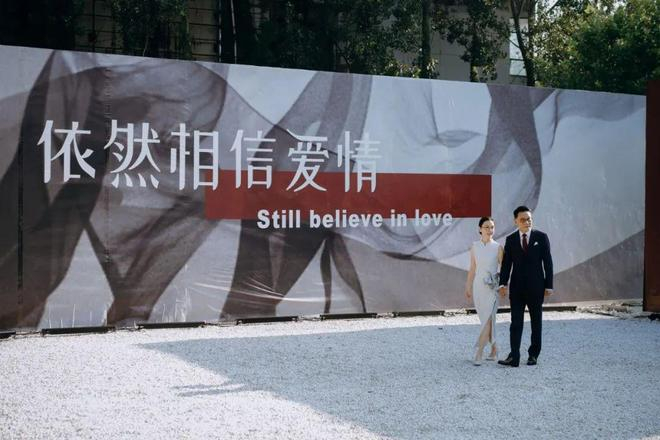 李国庆牵着张丹红的手在“依然相信爱情”的海报前合影