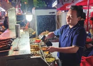 长沙市芙蓉区“忆口香”门前的烧烤摊，张青正在烤烤串。王智芳 摄