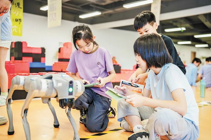 在浙江大學(xué)，小朋友正在學(xué)習(xí)控制機(jī)器狗。邱旭斌 攝