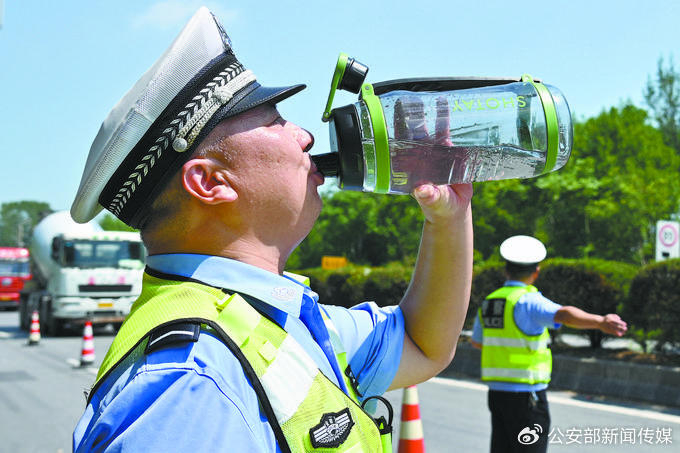 8月16日，安徽省固镇县公安局交管大队民警辅警在101省道指挥疏导交通。图为辅警在换岗空档饮水解暑。吴献永 摄