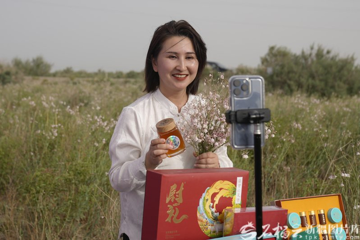 尉犁县直播基地主播走进田间地头，直播销售罗布麻花蜜。尉犁县直播基地供图