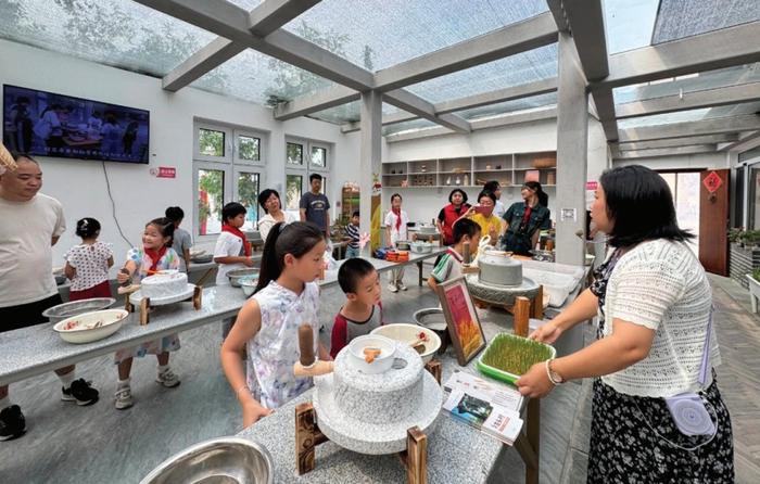 图为学生们在北京市大兴区礼贤镇龙头村体验石磨面粉与石磨豆浆等传统手工艺。