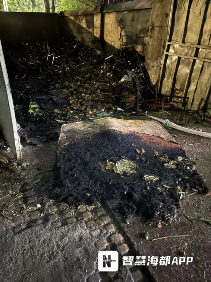 垃圾屋內(nèi)部物品已被燒焦，門(mén)口擺放著一張過(guò)火嚴(yán)重的垃圾床墊