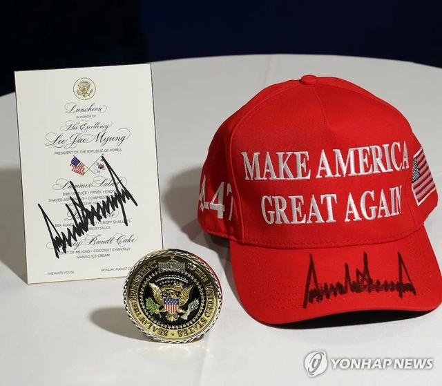 图为特朗普向李在明赠送的白宫纪念章以及其签字的“MAGA”帽子和午餐菜单。 图片来源：韩国联合通迅社